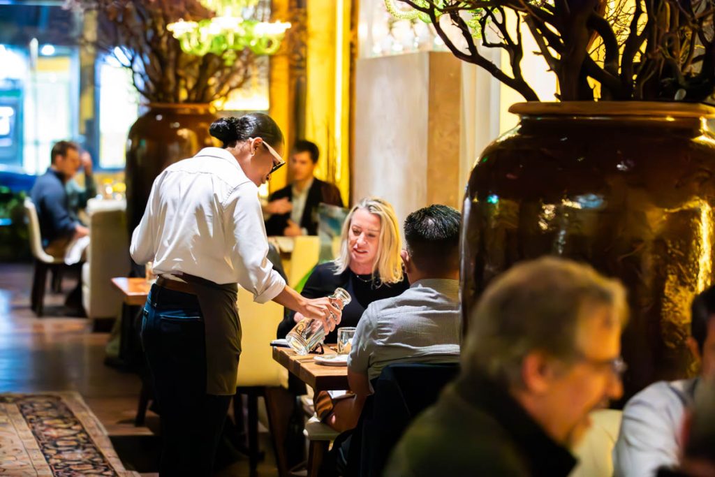 A server pours water for a table at in the Guild House dining room.