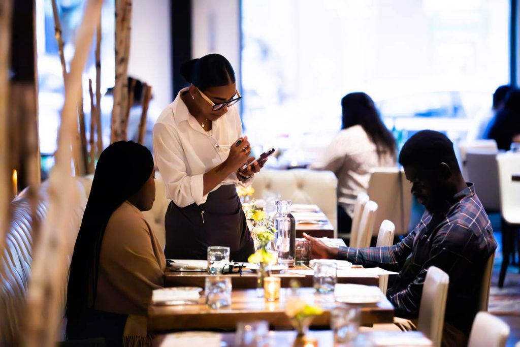 A server at the Guild House takes the order of two guests.